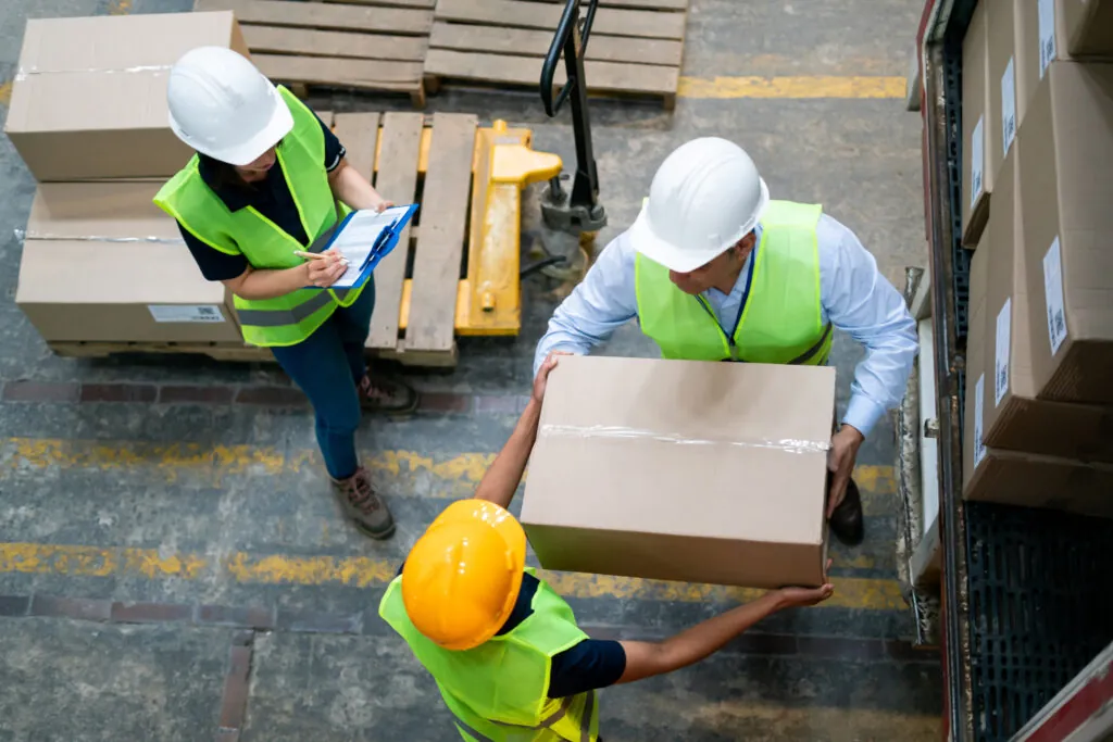 Group of Latin American warehouse workers loading a truck with boxes to distribute