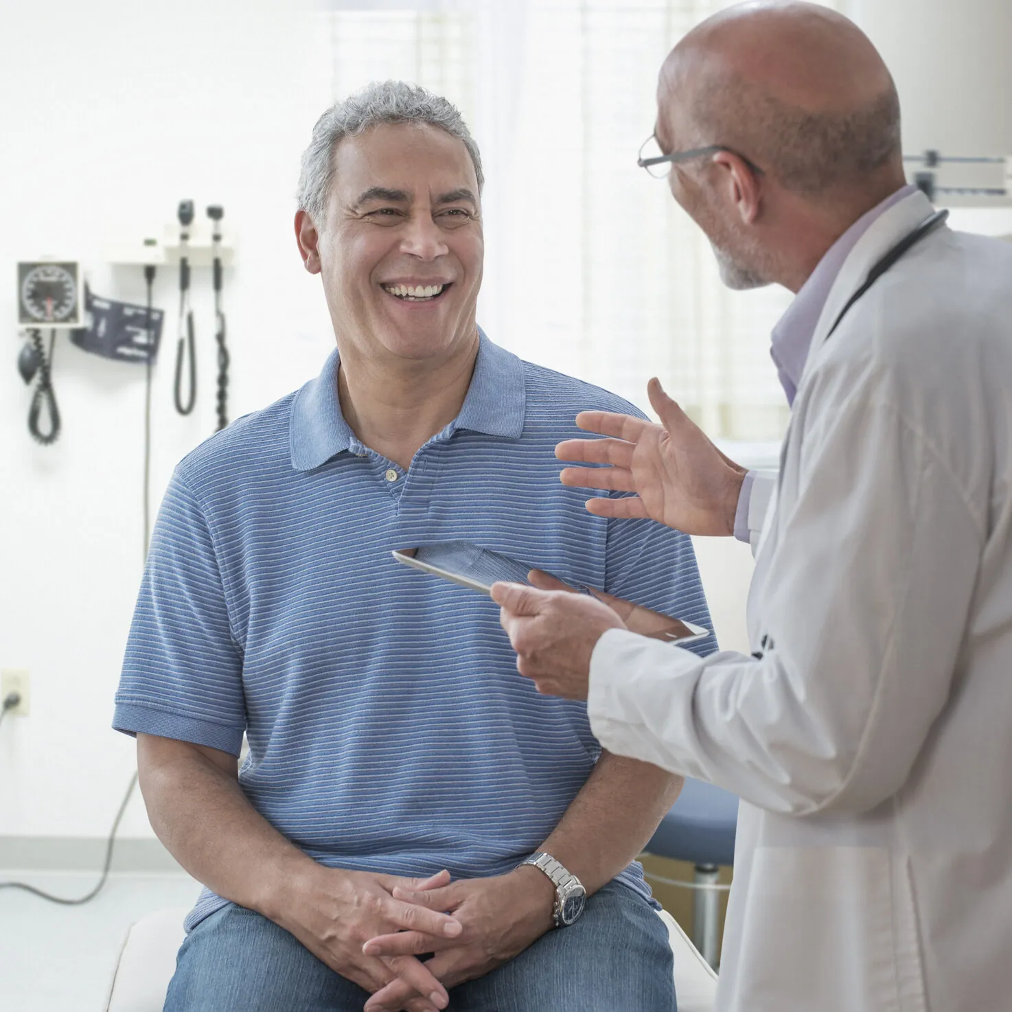 Doctor using digital tablet and talking to patient in office